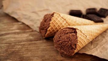 Chocolate ice cream in a waffle cone on craft paper photo