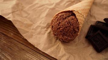 Chocolate ice cream in a waffle cone on craft paper photo