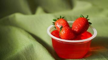 Red strawberry jelly with berries in a plastic container photo