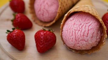 helado de fresa en un cono de galleta. frutos rojos y bolas de helado foto