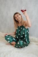 Girl in green pajamas in bed with a glass of red wine photo