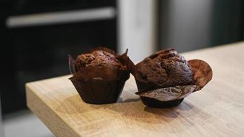 Dos muffins de chocolate sobre una mesa de madera contra la cocina moderna foto