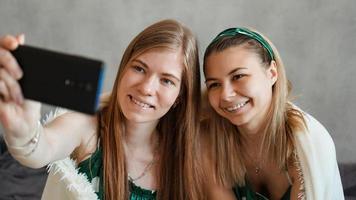 Beautiful happy girlfriends taking selfie with smartphone photo