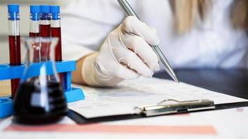 Woman working with blood samples in laboratory, closeup photo