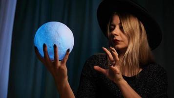 A young woman fortune teller in a hat is holding a magic ball. photo