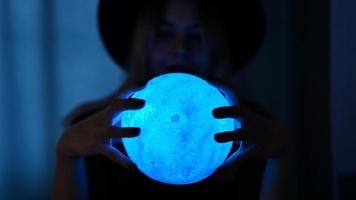 A young woman fortune teller in a hat is holding a magic ball. photo