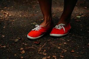 Legs in red sneakers on an autumn path in the park. Black leather legs photo