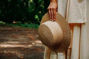 Close-up photo of a woman's hand holding a straw hat