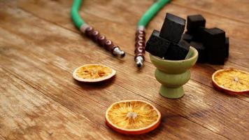 Coals for hookah on wooden background with dry oranges photo