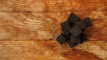 Cubes of coconut coal for hookah on wooden background. photo