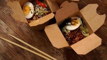 Chinese noodles with chicken in cardboard boxes on a wooden background photo