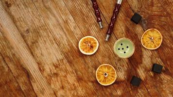 Cuenco de narguile sobre fondo de madera con naranjas secas foto