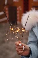 Female hands are holding burning sparklers. Woman outdoors photo