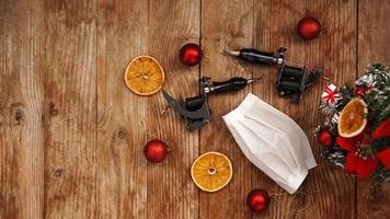 Tattoo machine with protectives face mask on a christmas background photo