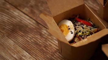 Chinese noodles with chicken and egg in cardboard photo