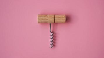 Wooden hand corkscrew on pink background photo