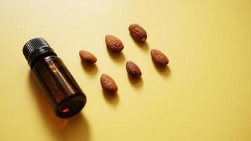 Bottle of almond oil and almonds on yellow background photo