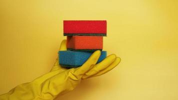 Hand in glove holding few washing sponges photo