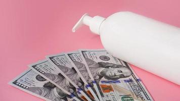 A white antiseptic pump bottle and money on a pink background photo