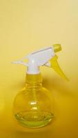 Spray bottle on yellow background photo