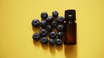 A bottle of blueberry seed essential oil and fresh blueberries