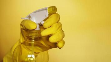 Hand in yellow rubber glove holding plastic spray photo