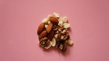 A handful of nuts on bright pink background, color background photo