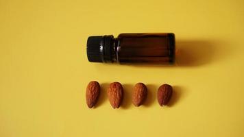 Bottle of almond oil and almonds on yellow background photo