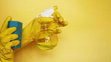 Hand in a rubber glove holds a cleaning sponge on a yellow background photo