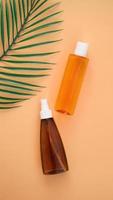 Suntan lotion bottle on background with tropical leaf. photo
