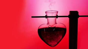 Open heart-shaped bottle of red love potion on a blurred background photo