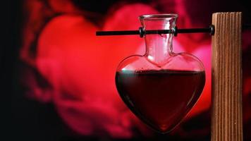 Open heart-shaped bottle of red love potion on a blurred background photo