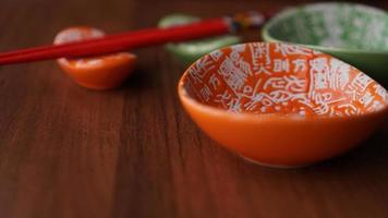 Set of ceramic dishes and red sushi sticks on wooden background photo