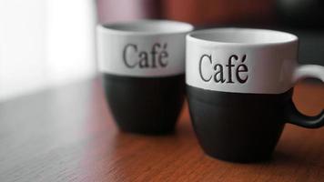 Two little coffee cups over a wooden table with a blurred background photo