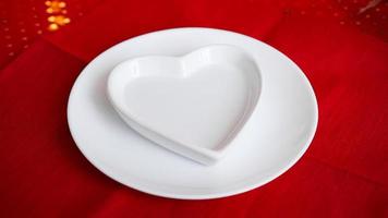 Heart shaped white plate on red photo