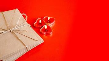 Kraft paper envelopes with red candles on a red background. photo