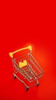 Empty small yellow shopping cart on red photo