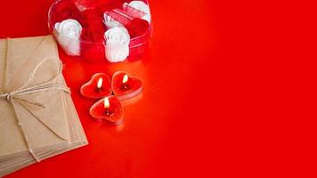 Kraft paper envelopes with red candles on a red background. photo