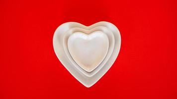 Heart form white plates on red background photo