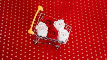 Flor de rosas rojas y blancas en el carrito de la compra en rojo