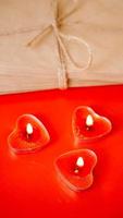 Kraft paper envelopes with red candles on a red background. photo