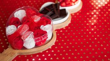 Roses, chocolates and sweets on heart-shaped plate photo