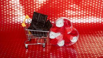 Chocolate in shopping trolley and roses on red photo