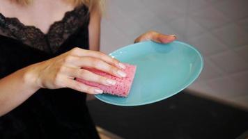 Blue plate with pink dish sponge in hand on blurred background photo