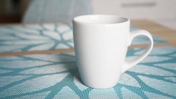 Clean white mug with handle stands on blue table photo