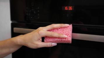 limpiar el horno en el exterior. una mano femenina limpia el panel del horno foto