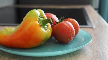 tomate y pimiento en una placa azul sobre un fondo claro en la cocina