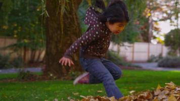 niños jugando en hojas de otoño. video