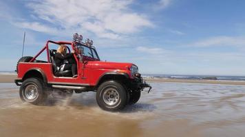 coppia alla guida di un fuoristrada 4x4 che guida sulla spiaggia video