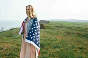 Una niña con un vestido coral y una chaqueta vaquera sostiene la bandera de EE. UU. foto